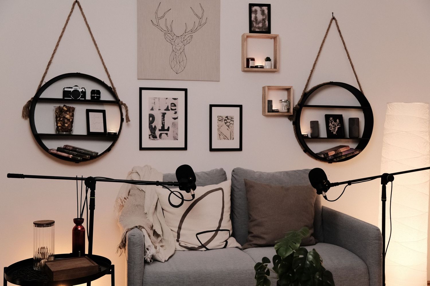 Cozy podcast corner with deer artwork, circular wall shelves, and microphone stands.