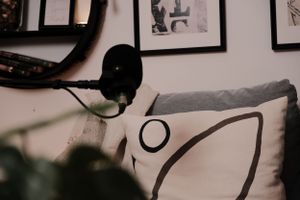 Close-up of podcast equipment with decorative cushions and wall art in warm ambient lighting.