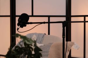 Silhouetted microphone equipment against backlit room divider with cozy cushions.