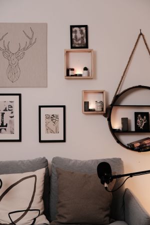 Living room wall decorated with framed art prints, deer motifs and floating wooden shelves.