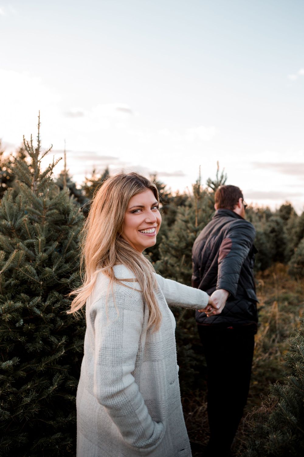 Couple strolling through Christmas tree farm at sunset.