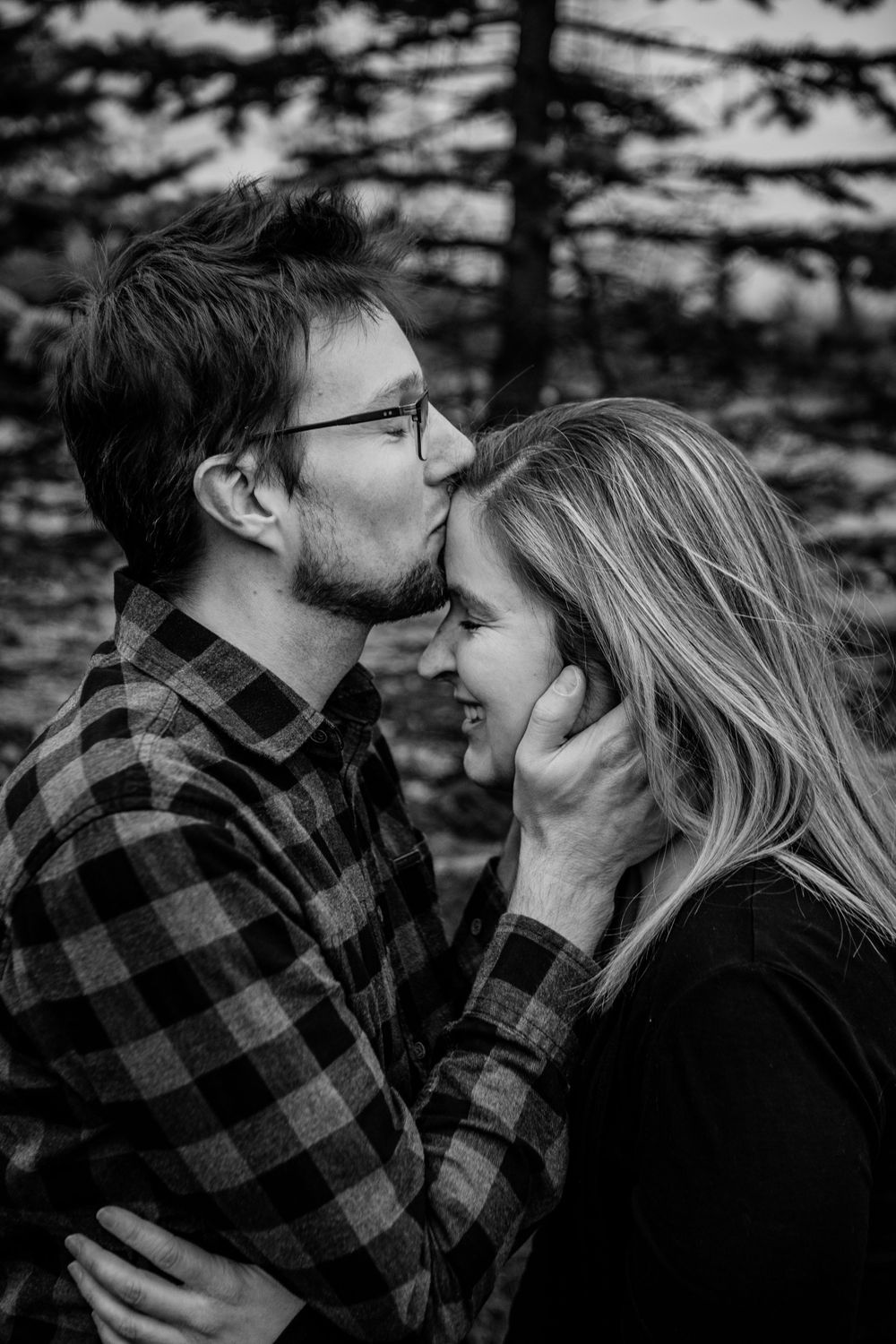 Black and white photos of a couple in a plaid flannel shirt sharing intimate moments in a forest setting.