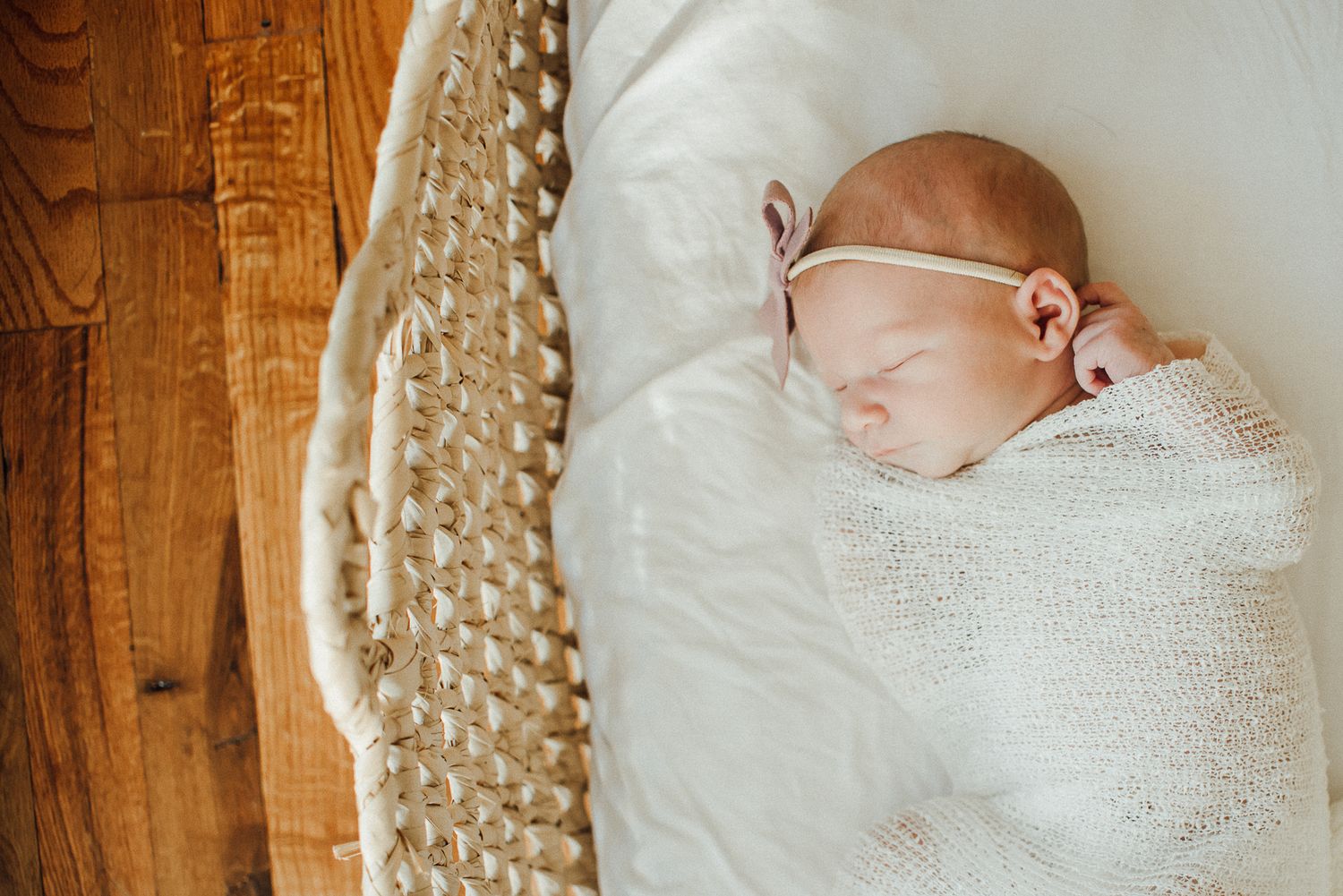 A newborn baby sleeping peacefully wrapped in white knit blanket.