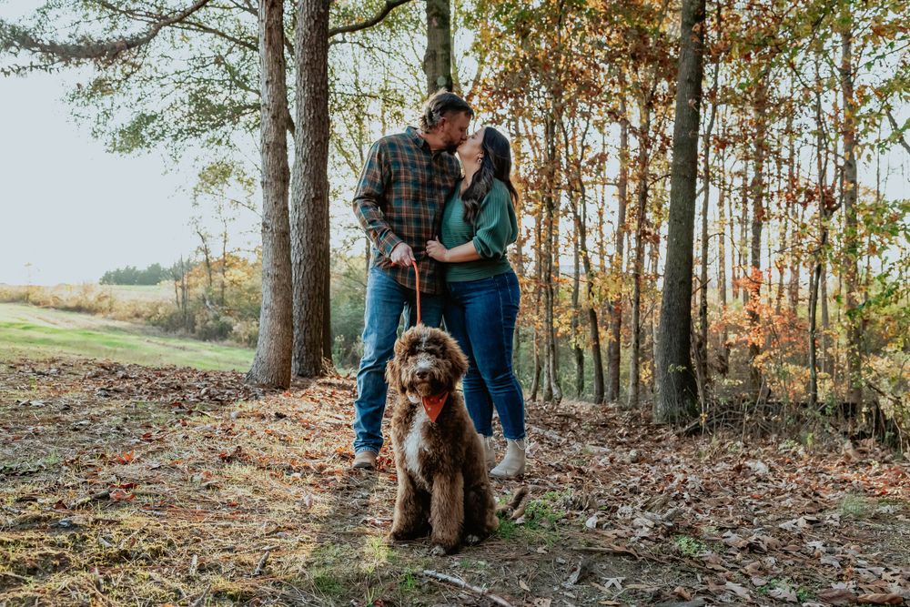 A family enjoys a playful moment together in an autumn forest setting.