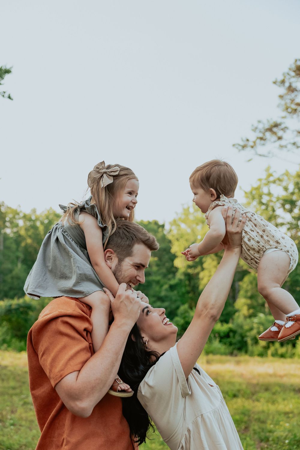 Joyful family moment outdoors with people lifting and playing together in a sunny field.