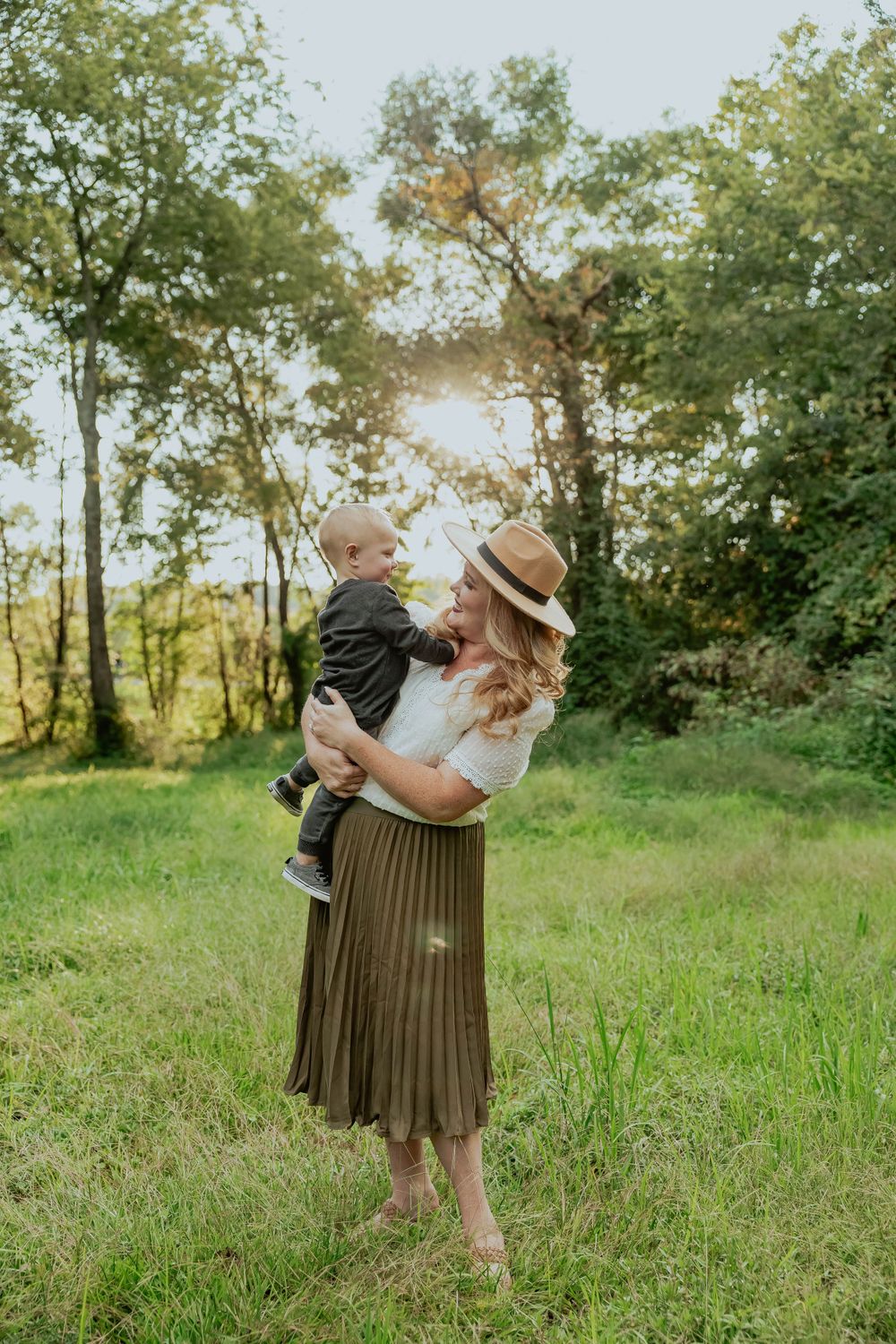 A sweet family moment captured in a grassy field during golden hour.