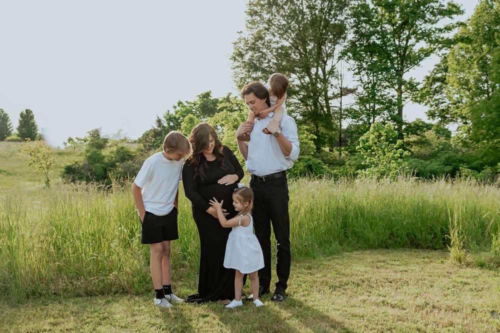 Family portrait session in a sunny meadow with tall grass and natural lighting.