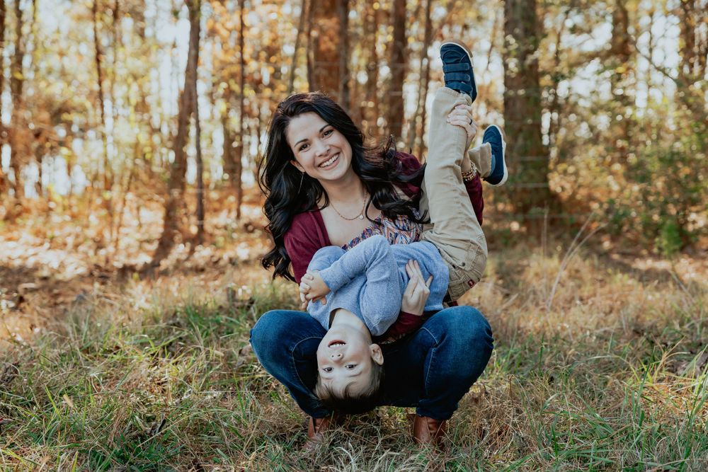 A candid family photoshoot in a wooded area with natural lighting.