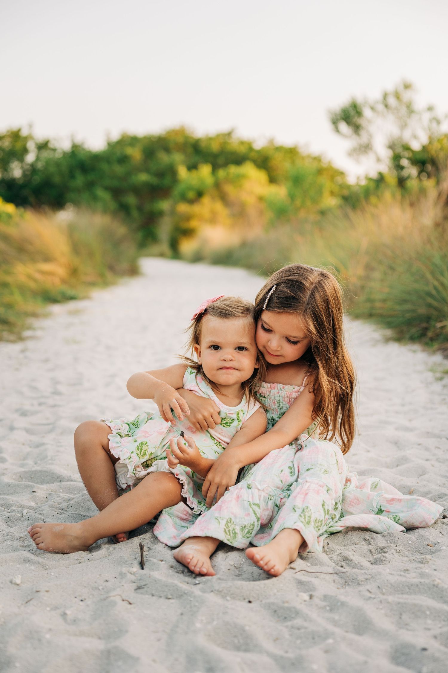 Young sisters playing in the sand at sunset on Siesta Key Beach photographed by Sarasota Family Photographer.