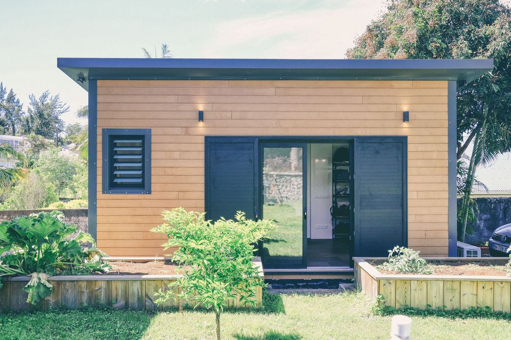 Modern beachside house exterior with wood siding and dark trim against tropical landscaping.