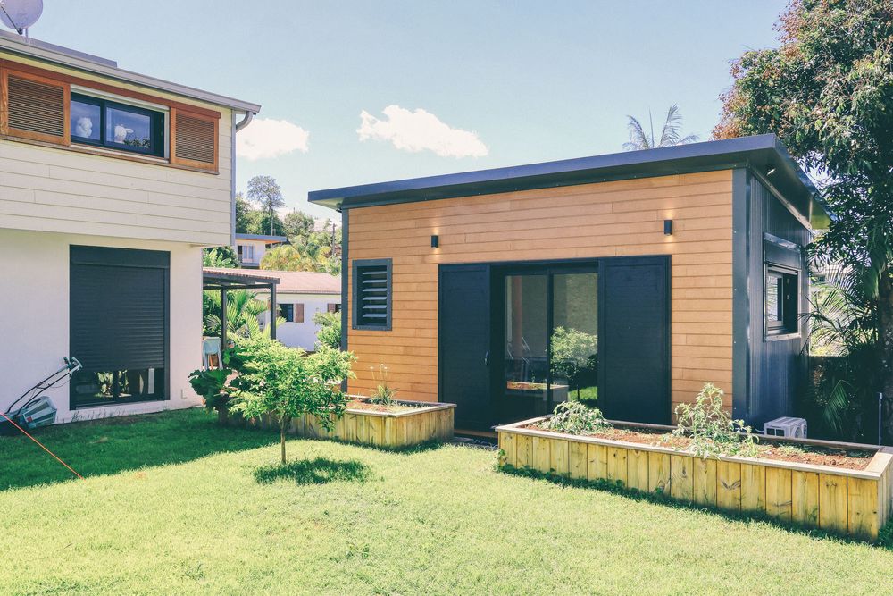 Contemporary wooden house exterior with black accents and fenced yard.