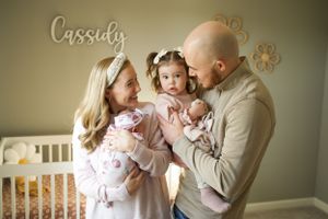 A tender family moment captured in a nursery with neutral tones and decorative wall accents.