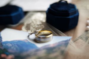 Wedding rings and jewelry details arranged on a textured blue surface.