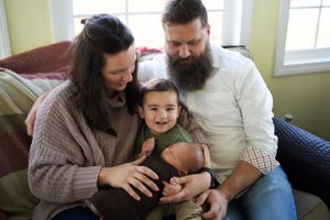 A family shares a joyful moment together on a couch in their living room.