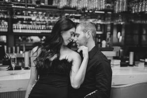 A romantic couple shares an intimate moment at a bar counter in black and white.