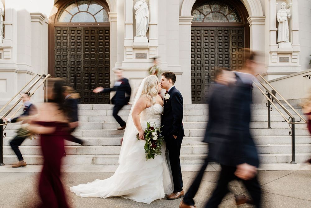 Elegant wedding ceremony on church steps with movement of guests creating artistic motion blur effect.