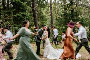 Joyous dancing celebration during an outdoor forest wedding reception.
