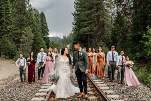 Wedding party posed on railroad tracks surrounded by evergreen forest.