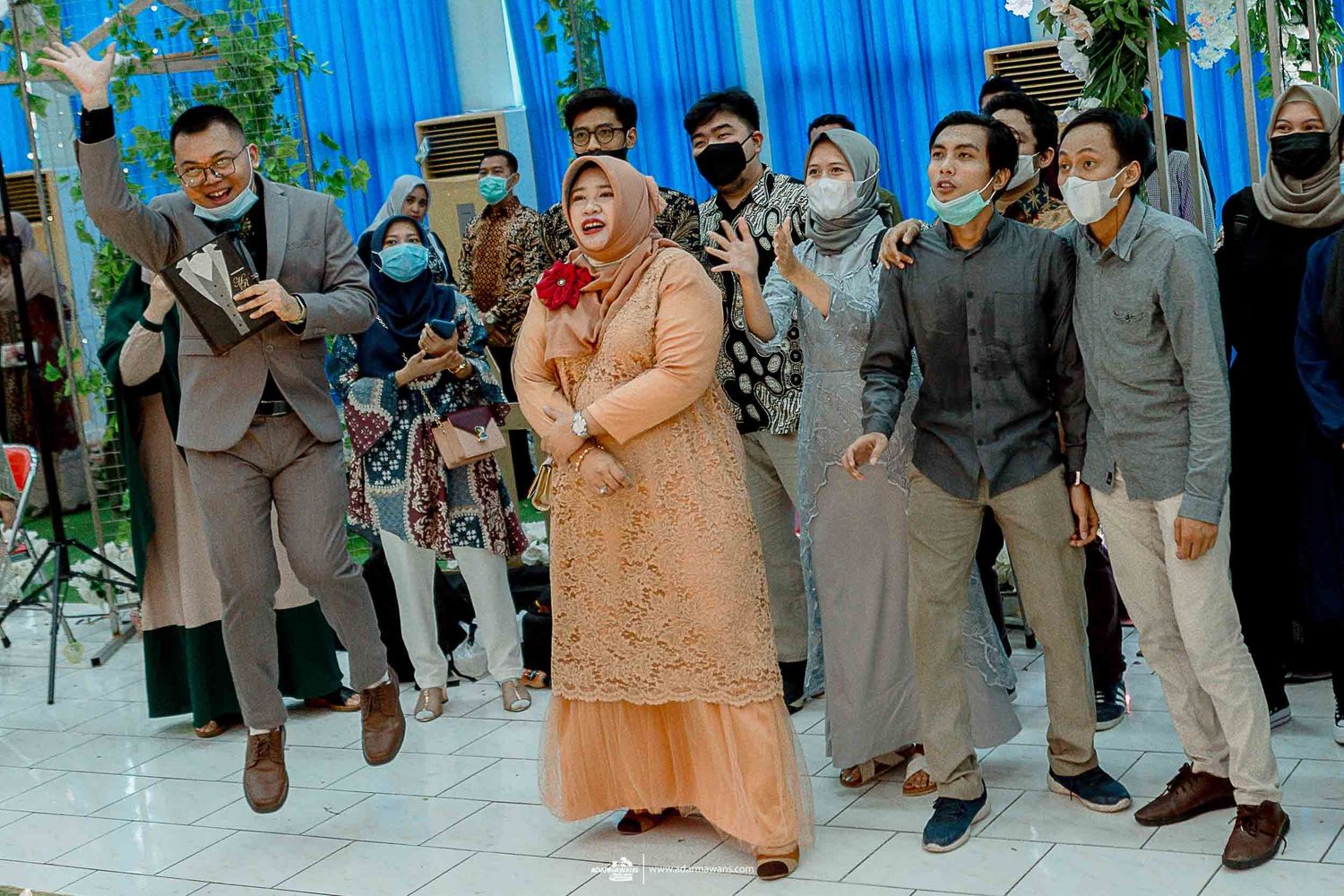 Wedding guests in formal attire celebrating during a festive indoor reception.