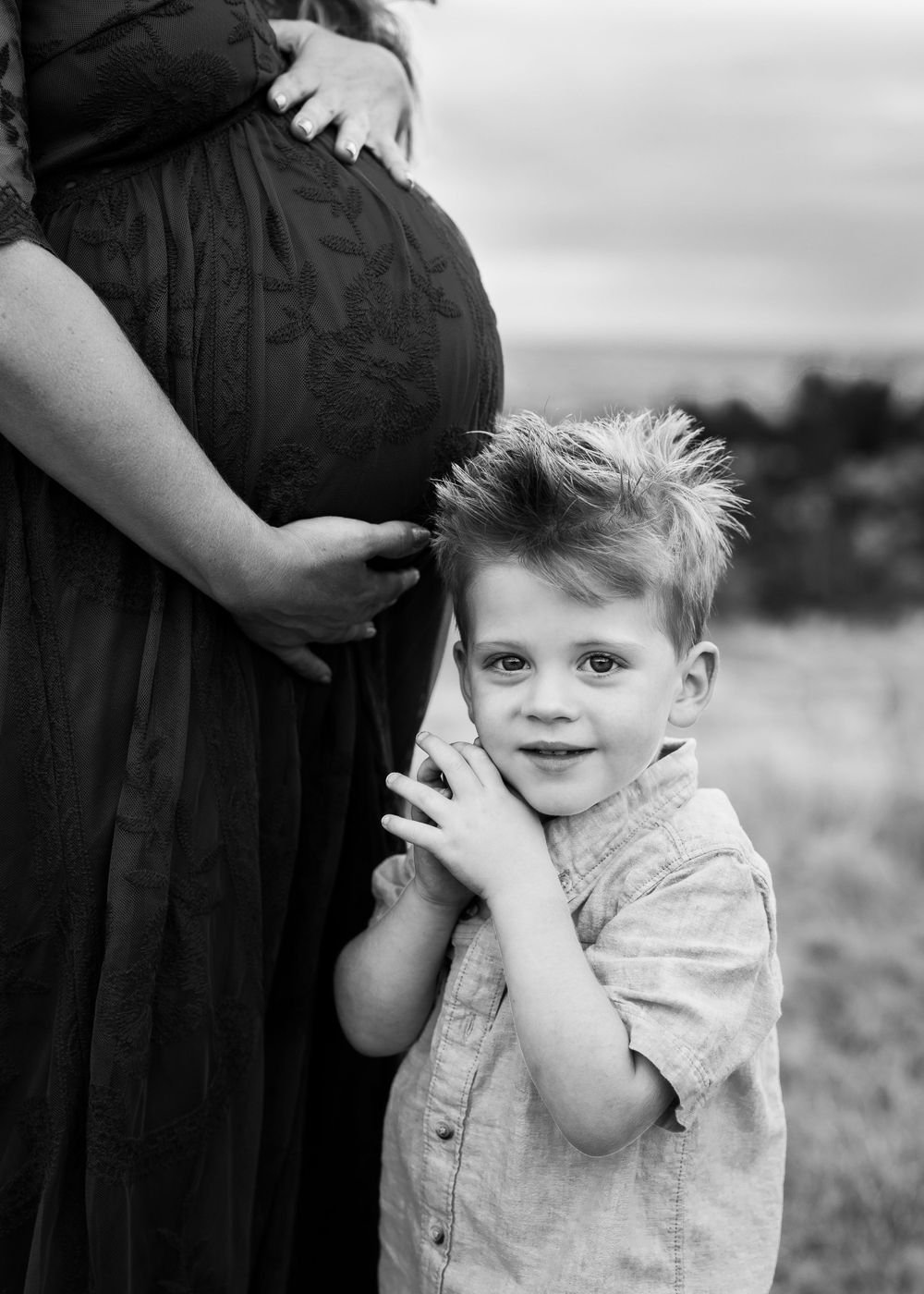Black and white photo of child touching pregnant mother's belly.