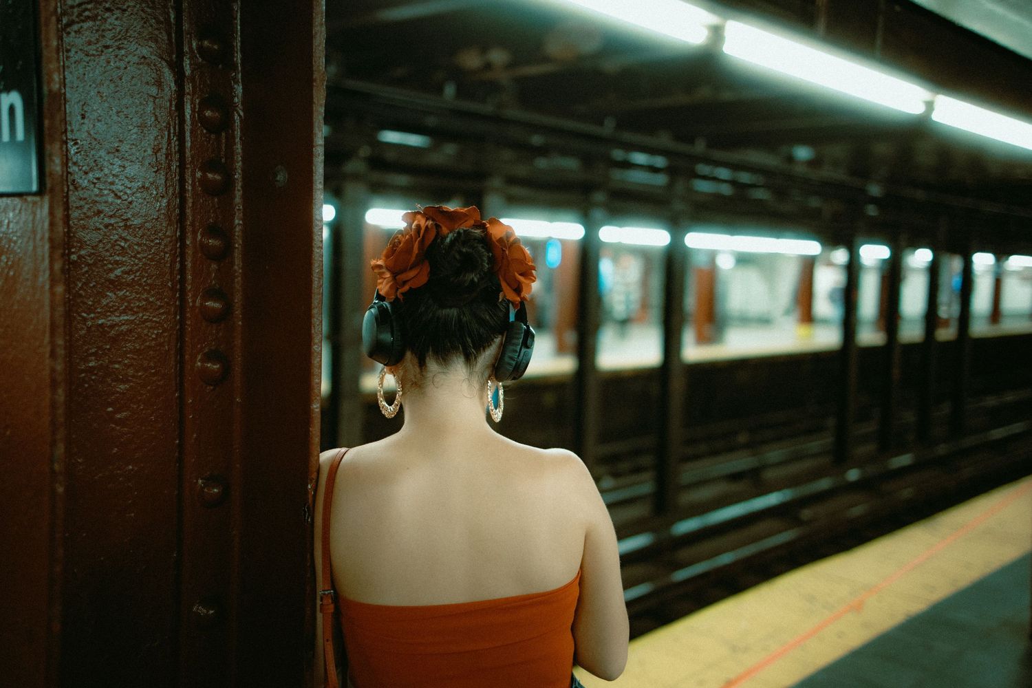 A figure in red waits on a subway platform next to dark tunnel walls.