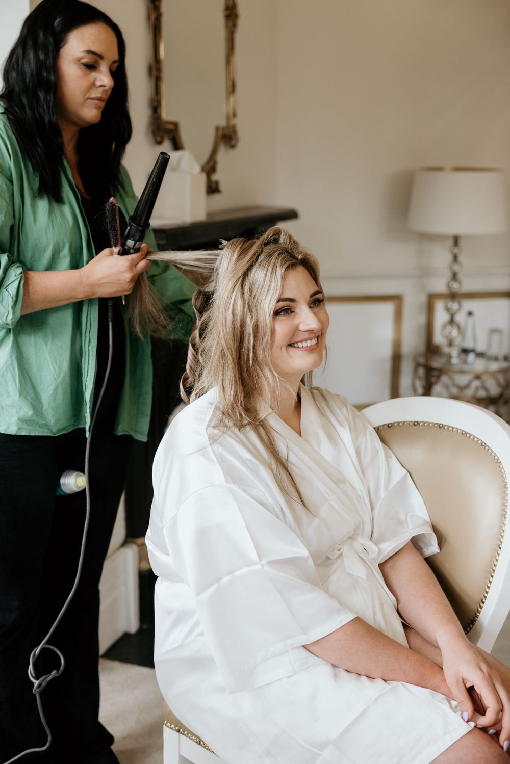 Hair styling session during bridal preparation in elegant white chair.
