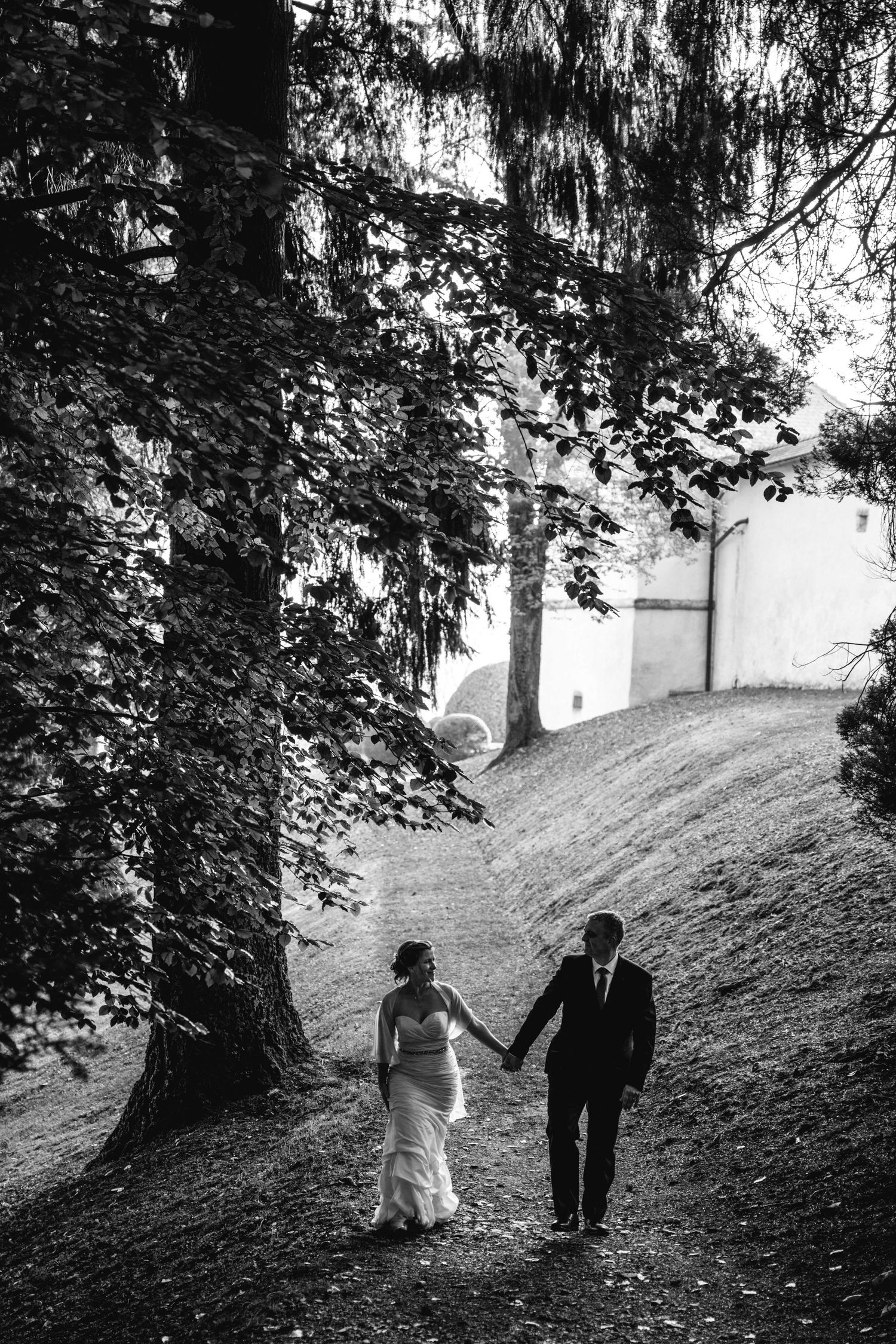 Black and white wedding photos of couple walking through tree-lined path.