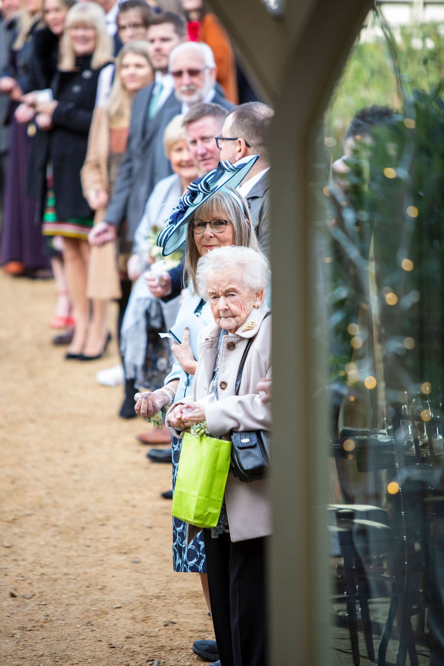 Wedding guests lined up outdoors viewing through decorative archway.