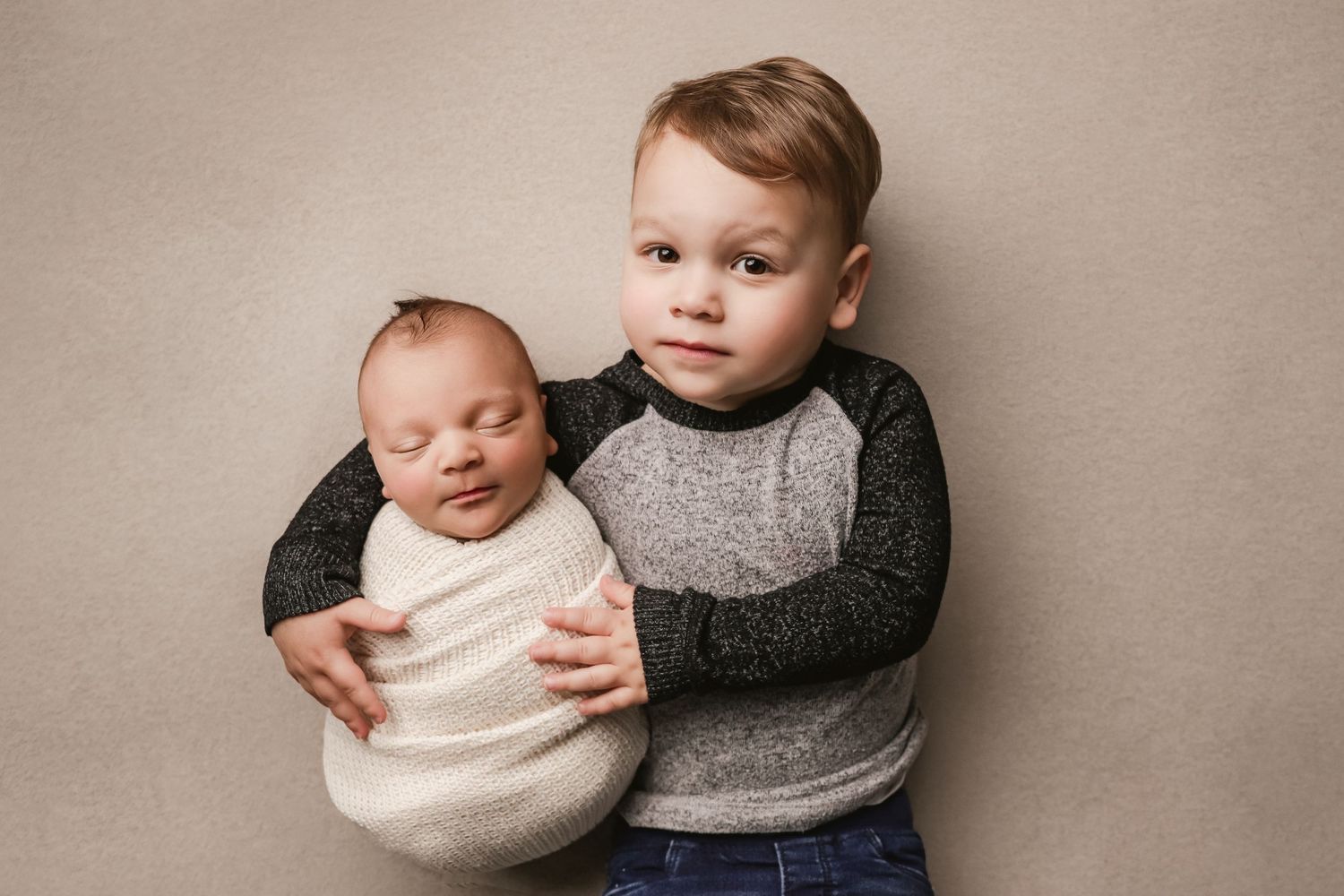 fine art newborn portrait with sibling wrapped in neutrals