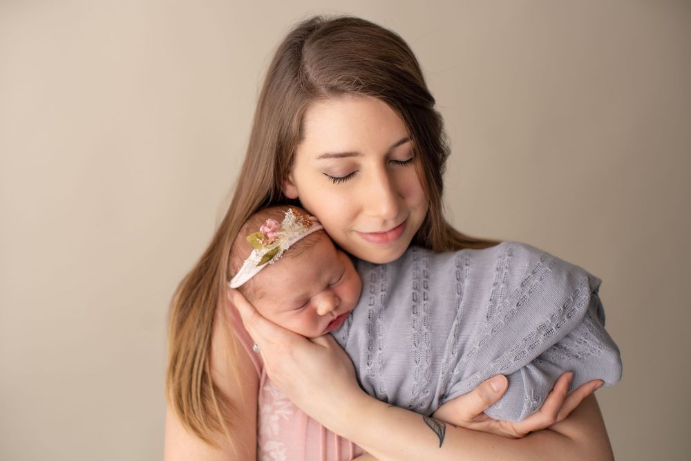 Tender newborn photography session showing gentle embrace in soft neutral tones.