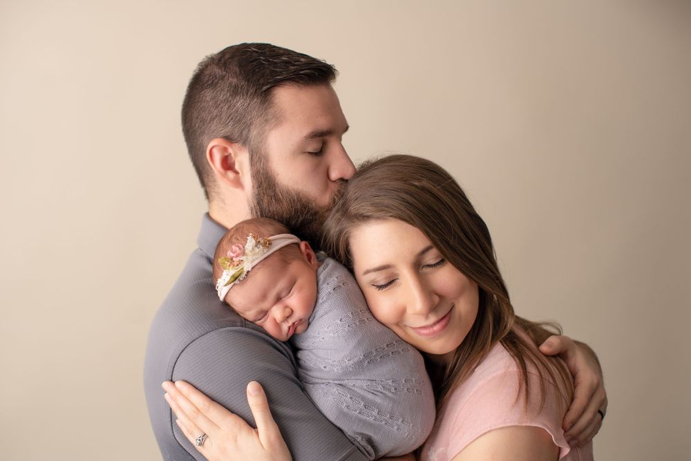 Gentle family moment captured during professional newborn photo session in studio setting.