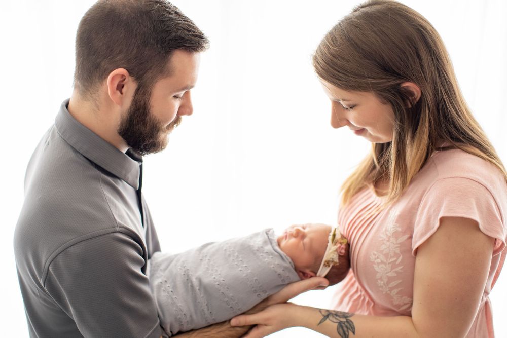 Intimate lifestyle portrait of family gazing at their newborn in natural light setting.