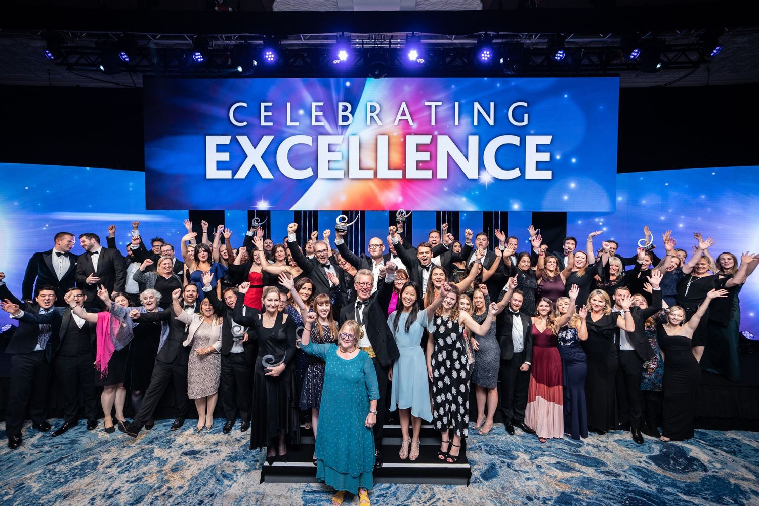 Celebrating Excellence award winners gathered on stage at the Grosvenor Hotel, Park Lane. Our Rates & Prices image
