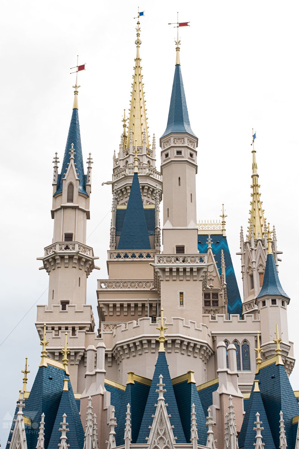 Cinderella Castle spires with gold and blue details against overcast sky at Disney World.