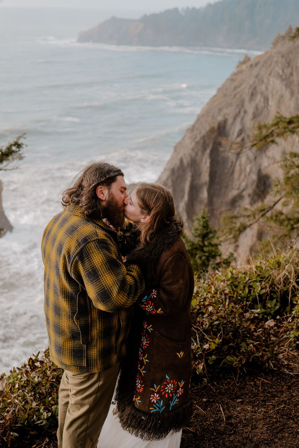 Bride and groom kissing next to costal cliffside