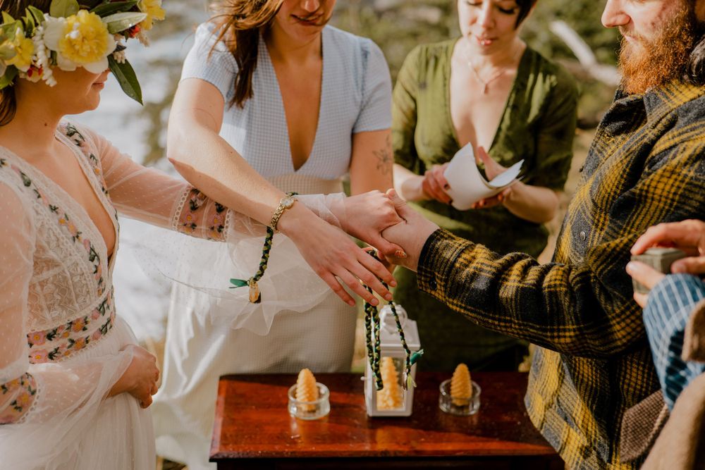 Officiant tying Bride and Grooms hands together with cord.