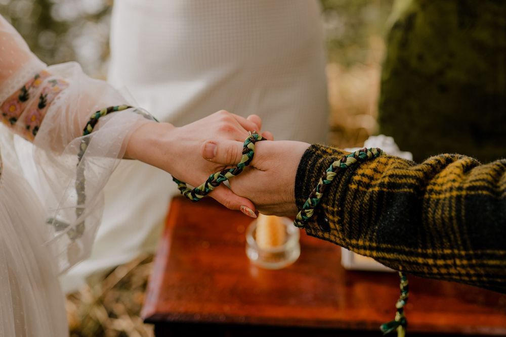 Bride and groom holding hands with cord wrapped around arm and wrist