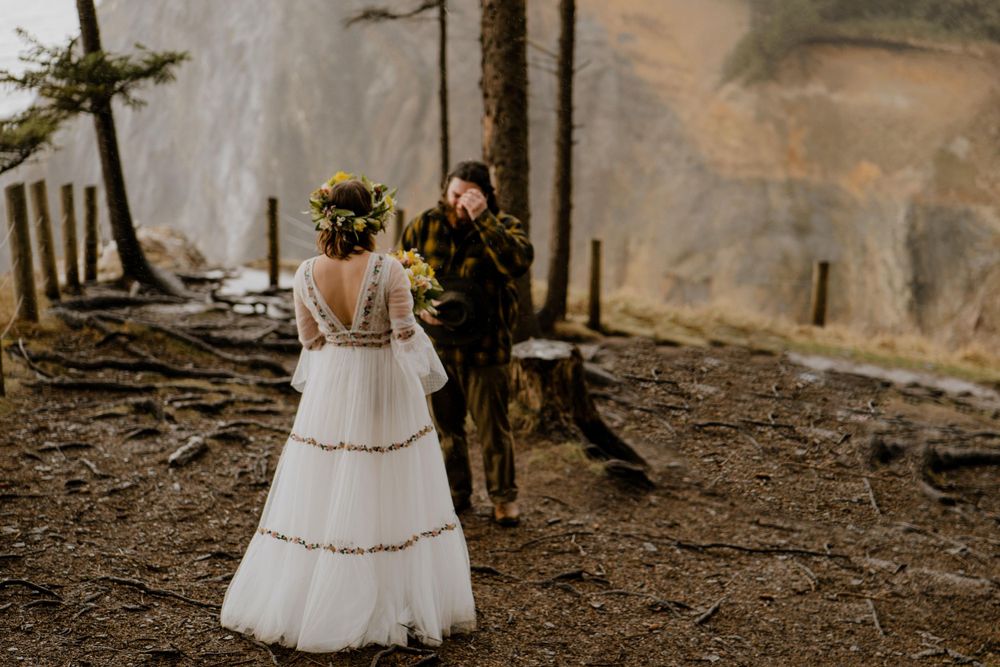 Groom crying during first look surrounded by trees
