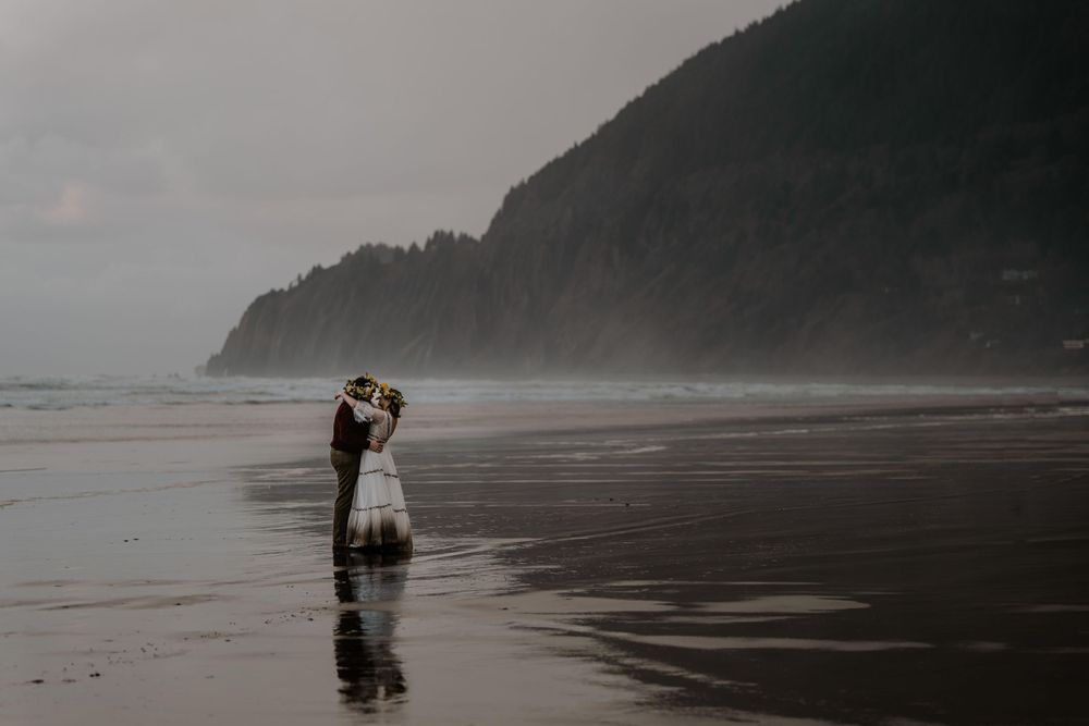 Bride and groom dancing in the tide of the oregon coast
