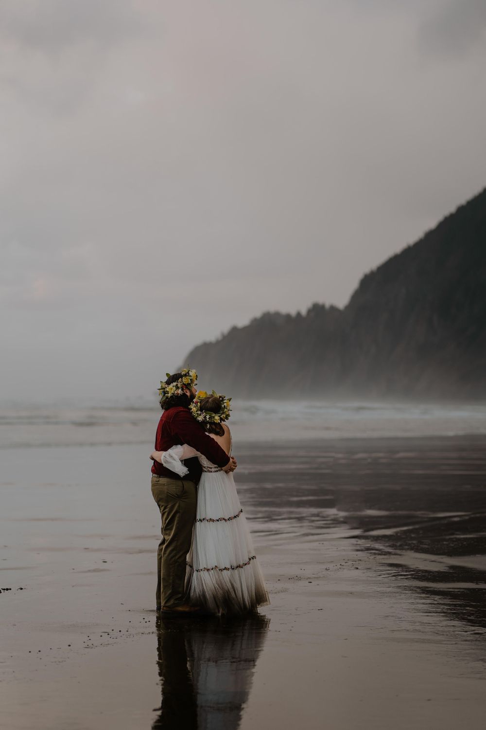 Birde and groom arm in arm looking at ocean horizon