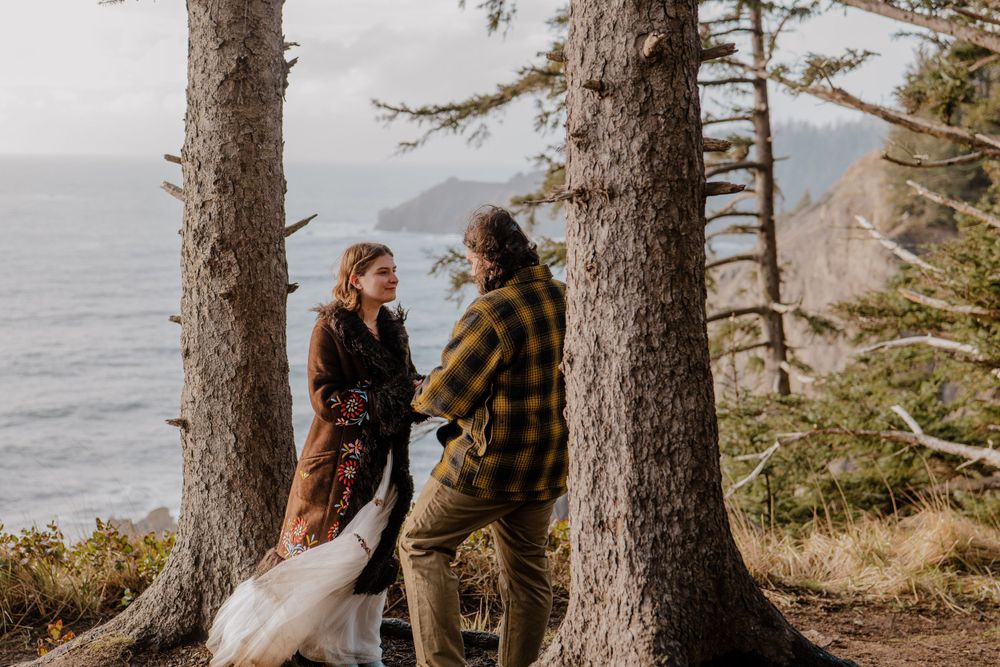 Bride and groom dancing between trees overlooking Oregon Coast