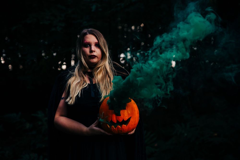 Dark Halloween scene with glowing jack o'lantern and teal smoke effects.