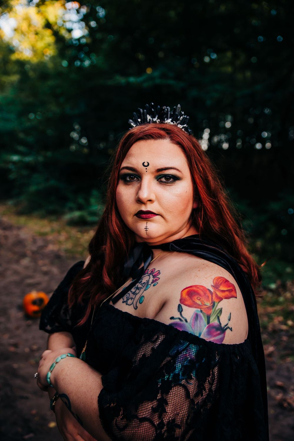 Gothic portrait featuring crystal crown, dark makeup and colorful shoulder tattoo.