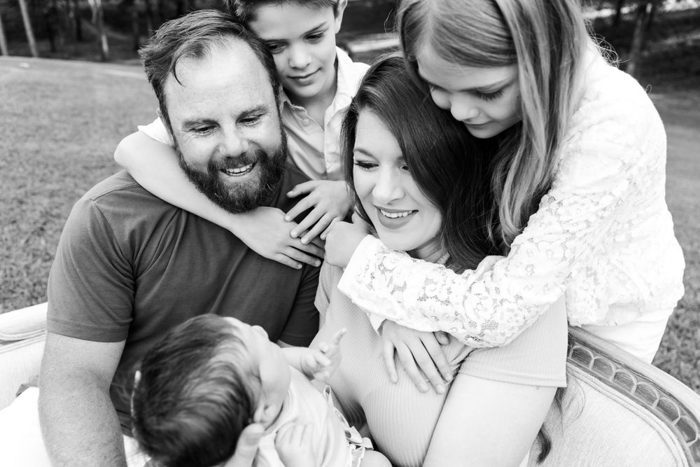 Family embracing and sharing intimate moments outdoors in black and white photography.