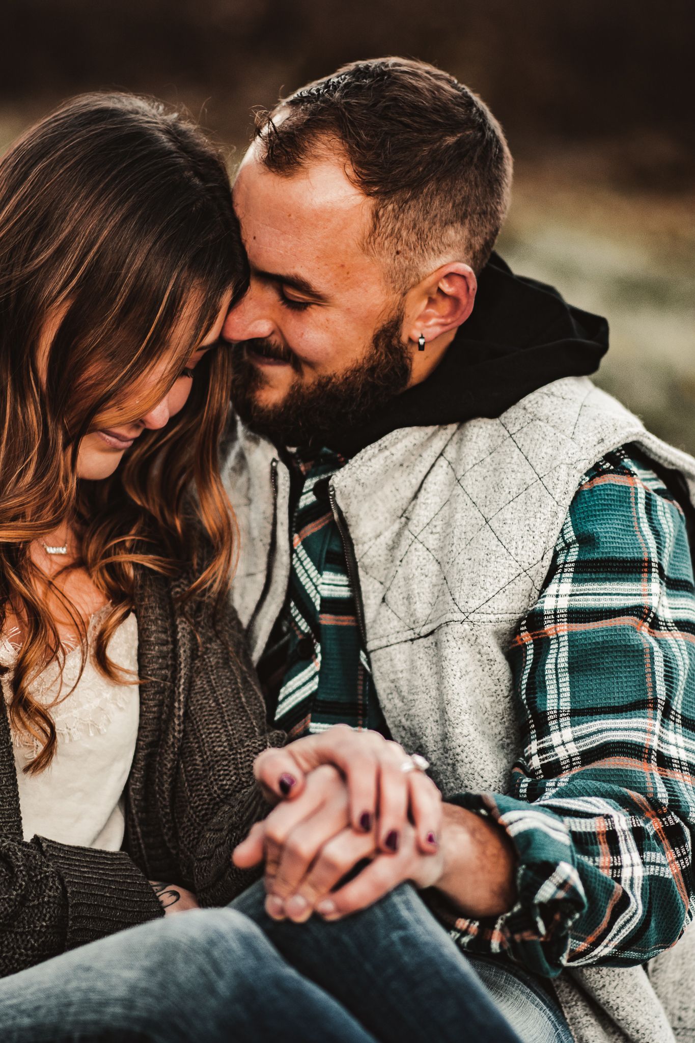 Couple sharing an intimate moment while holding hands on an autumn day wearing casual layered clothing.