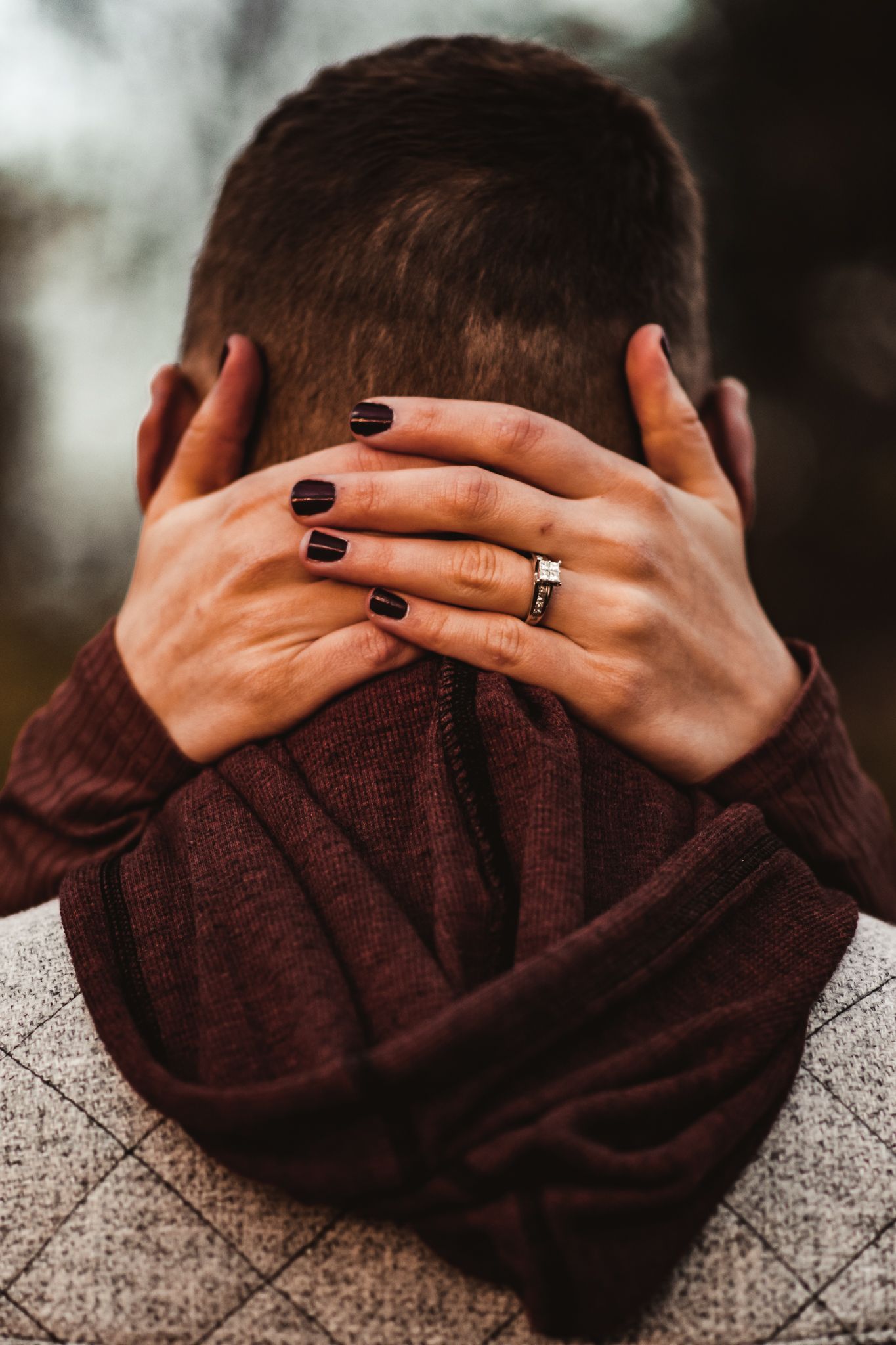 Close up of hands with engagement ring embracing on autumn day.