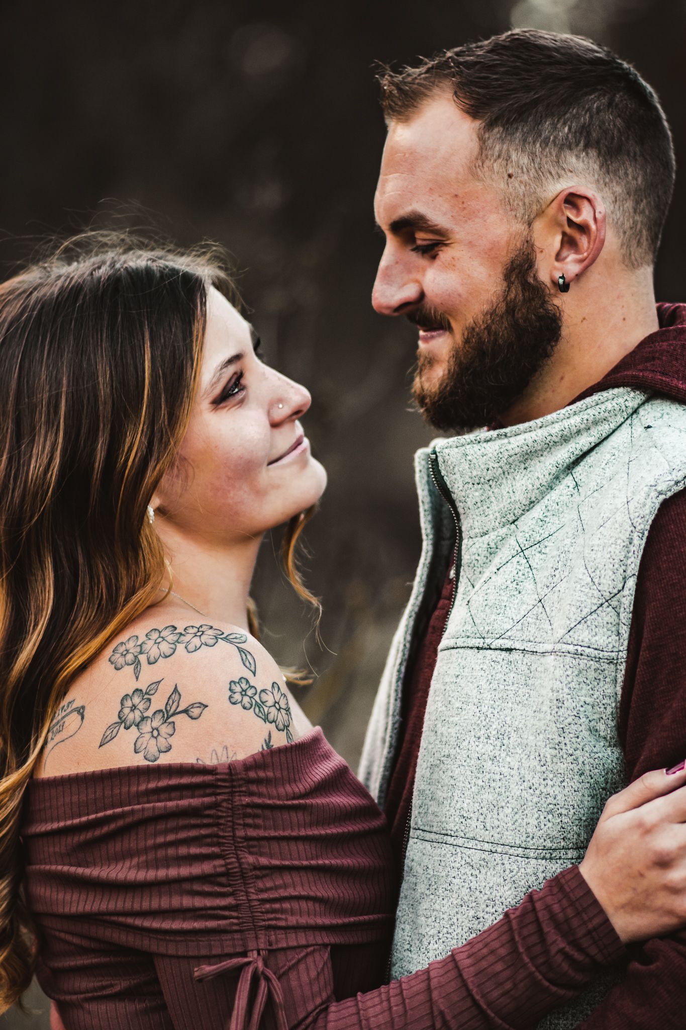 A couple in matching casual wear shares an intimate moment during their outdoor autumn photoshoot.
