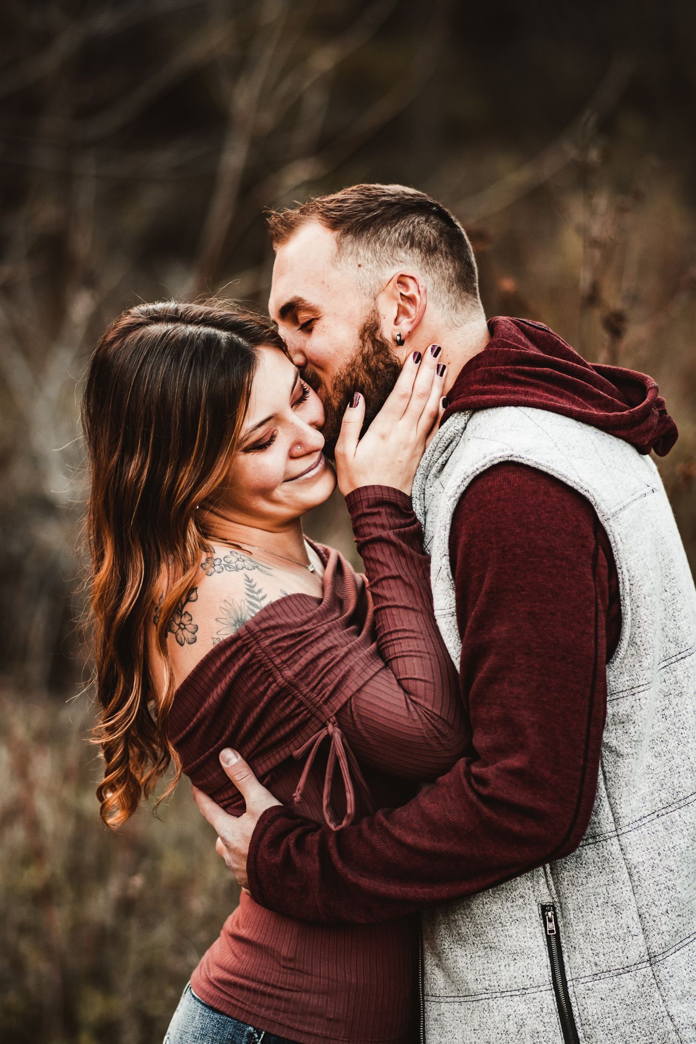 An affectionate couple embraces during their fall photo session in a natural outdoor setting.