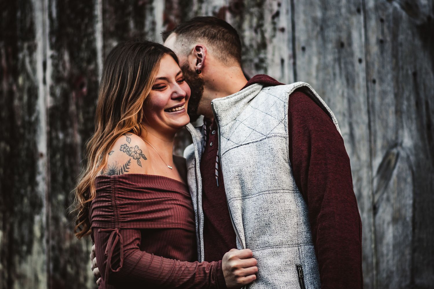 Couple sharing intimate moment against rustic wooden wall background.