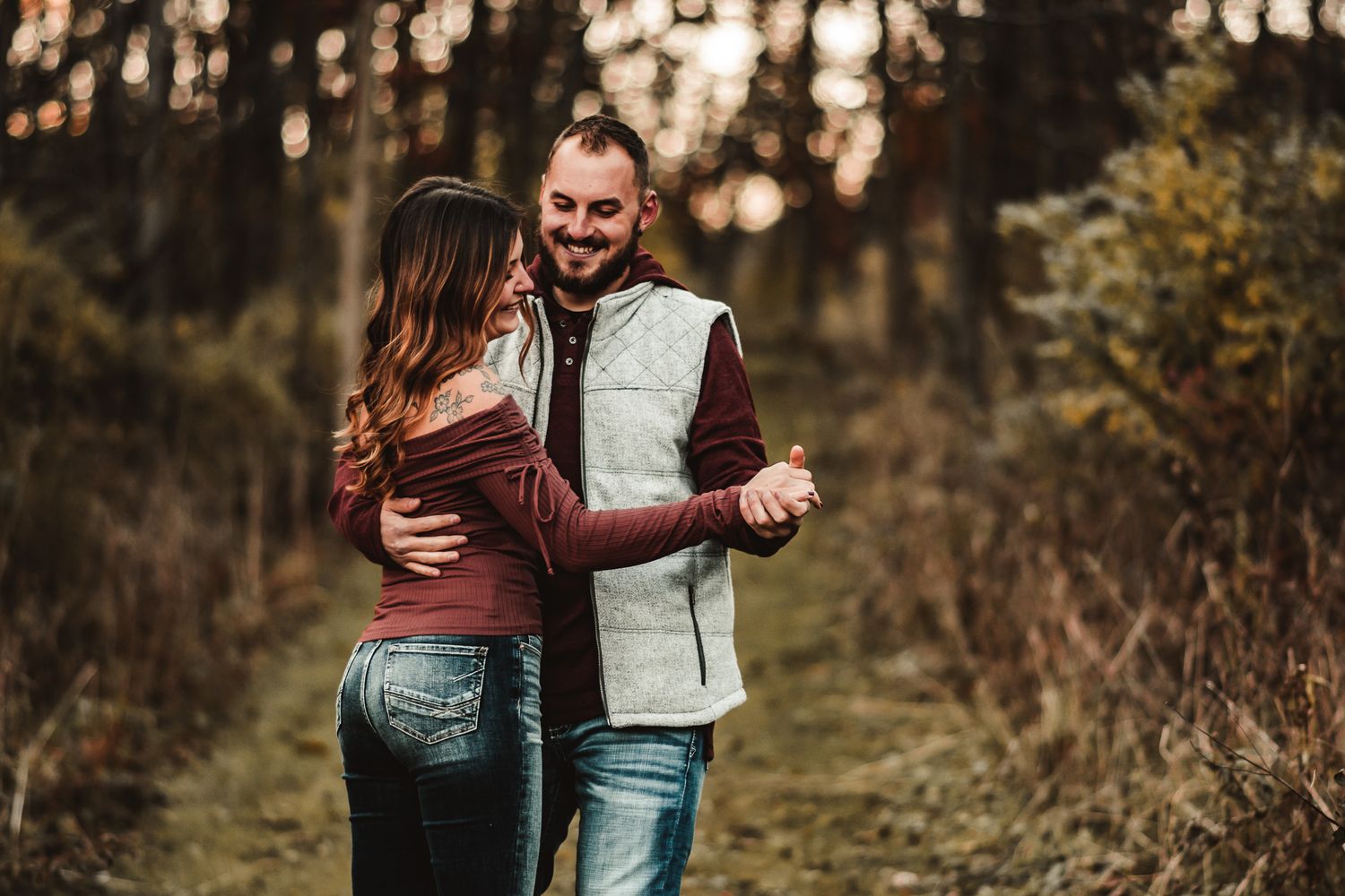 Romantic couple walking together on autumn path with sunlit bokeh background.